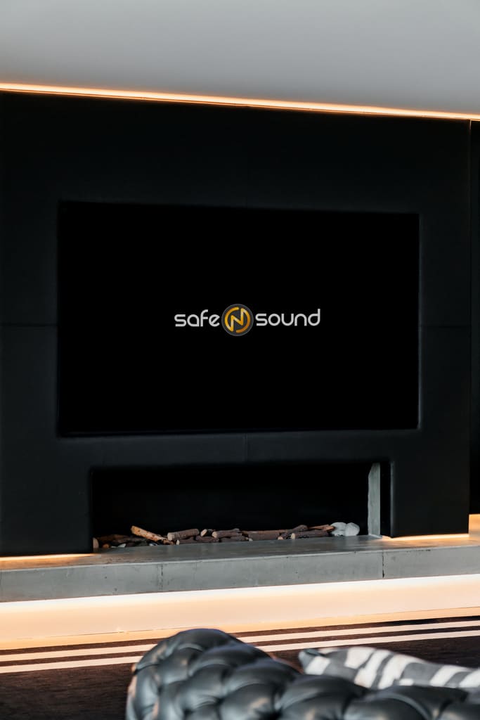 Modern minimalist living room featuring a sleek black marble fireplace, a large flat-screen TV, and custom-designed entertainment center by Safe N Sound.